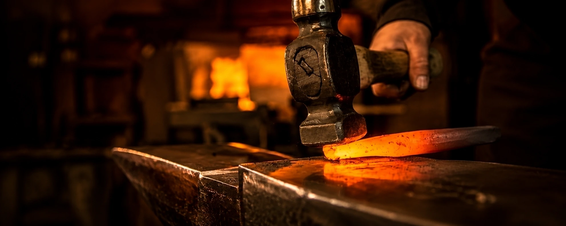 Hammer poised over a glowing orange billet on an anvil, the forge fire burning behind